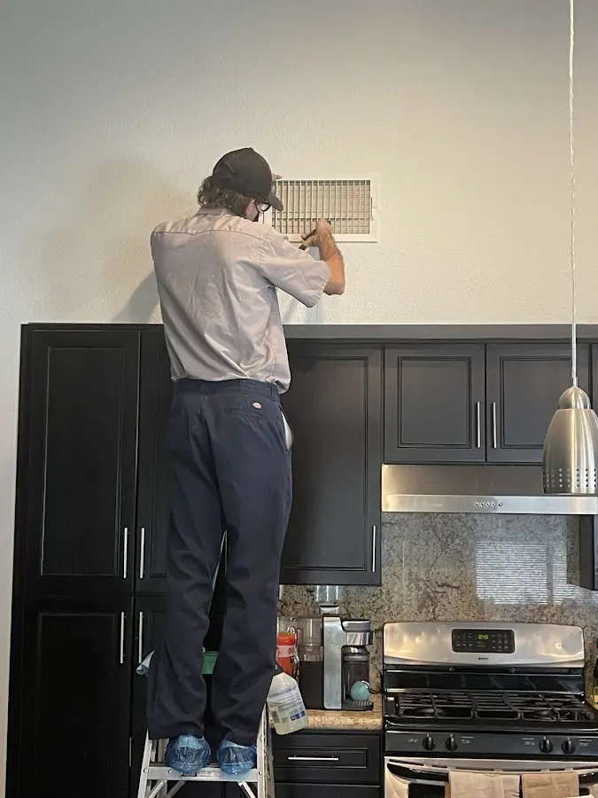 Technician inspecting an air vent during HVAC service in Rio Pinar